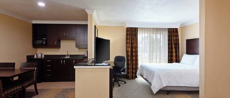 A hotel room with a bed, a desk, a chair, a television, and a microwave.