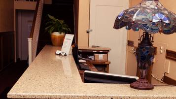 A reception desk with a wooden front, a sign reading "The Gilmore Hotel," and a decorative lamp.