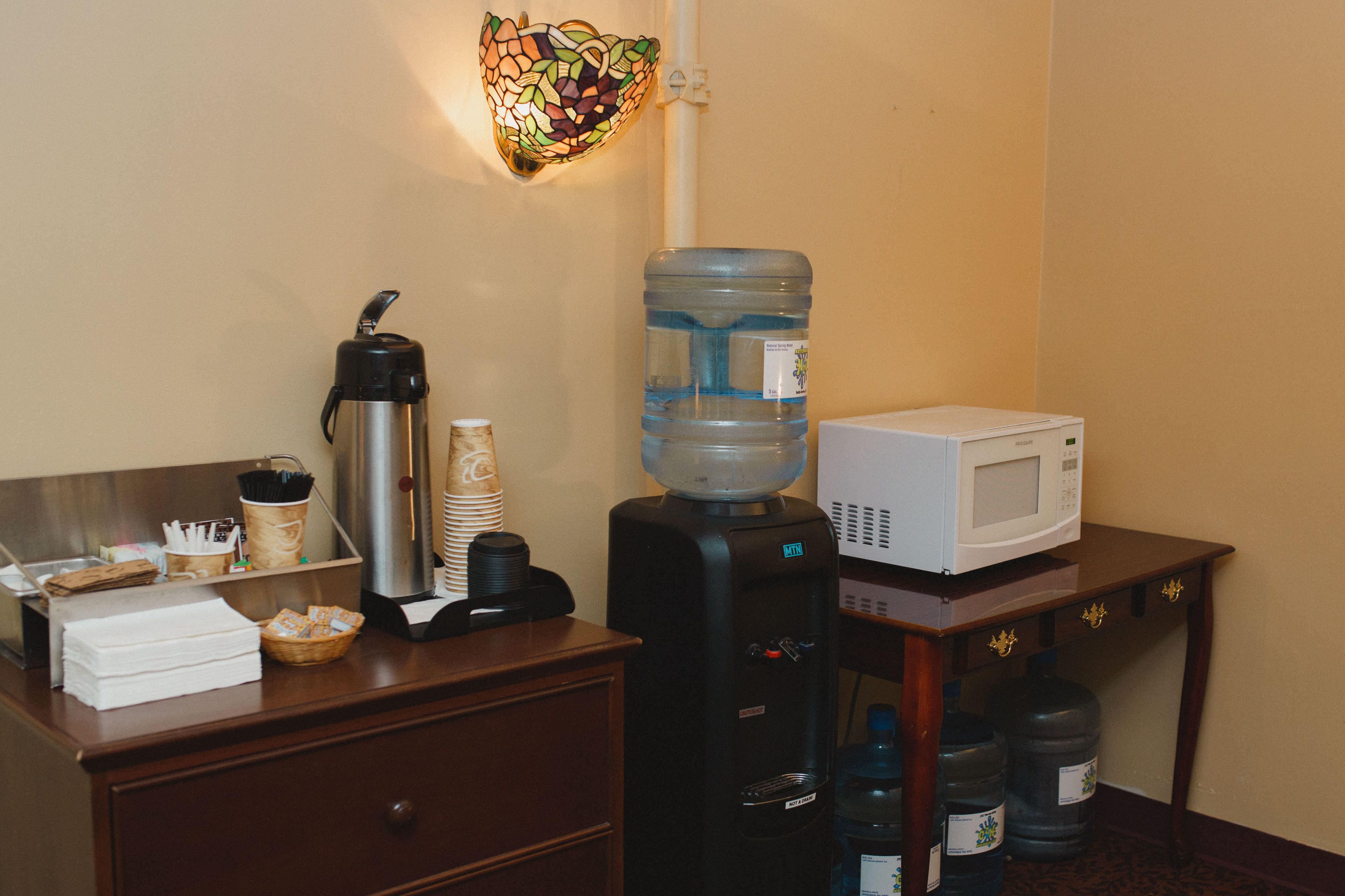 Habitación de hotel con kitchenette, que incluye cafetera, dispensador de agua, microondas y espacio para bebidas.
