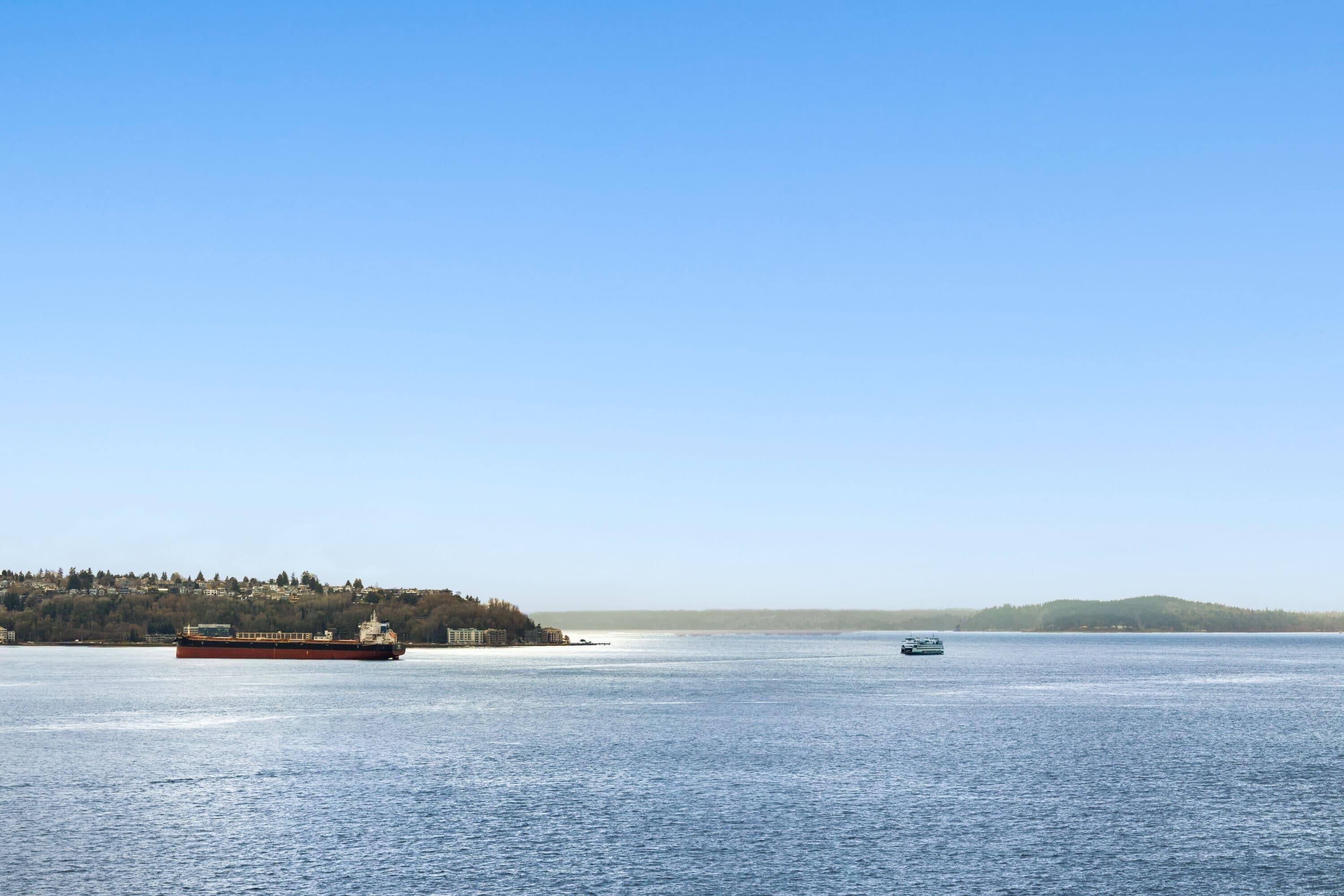 A large body of water with a ferry and a smaller boat.
