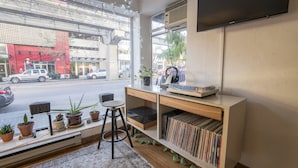 A modern room with a large window, a flat-screen TV, a bookshelf, and a small stool. - The Dylan, a Baymont by Wyndham (Seattle)