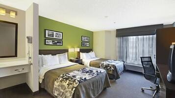 A hotel room with two beds, a desk, a chair, a TV, and a window with curtains.