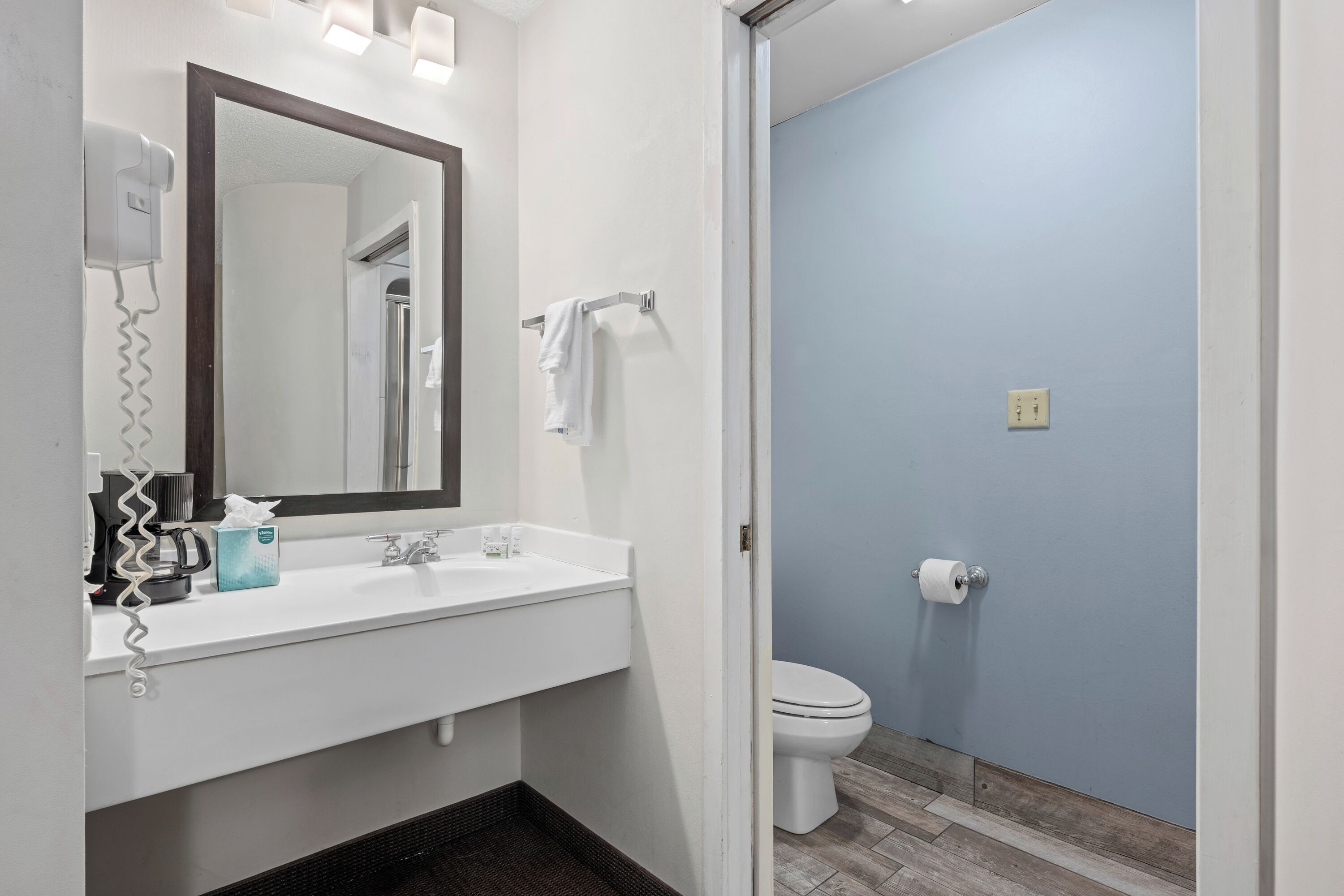 A bathroom with a white sink, a mirror, a towel rack, a toilet, and a hairdryer.