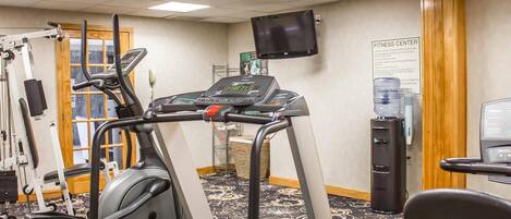 A fitness center with cardio machines, a television, and a water dispenser.