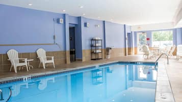 A swimming pool with chairs and tables, a tiled floor, and a blue wall.