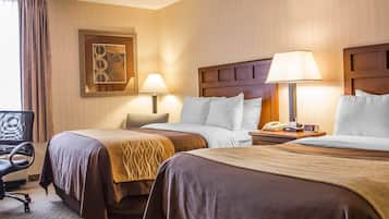 Een hotelkamer met twee bedden, een bureau, een stoel, een lamp, een klok en een lijst met een afbeelding aan de muur.
