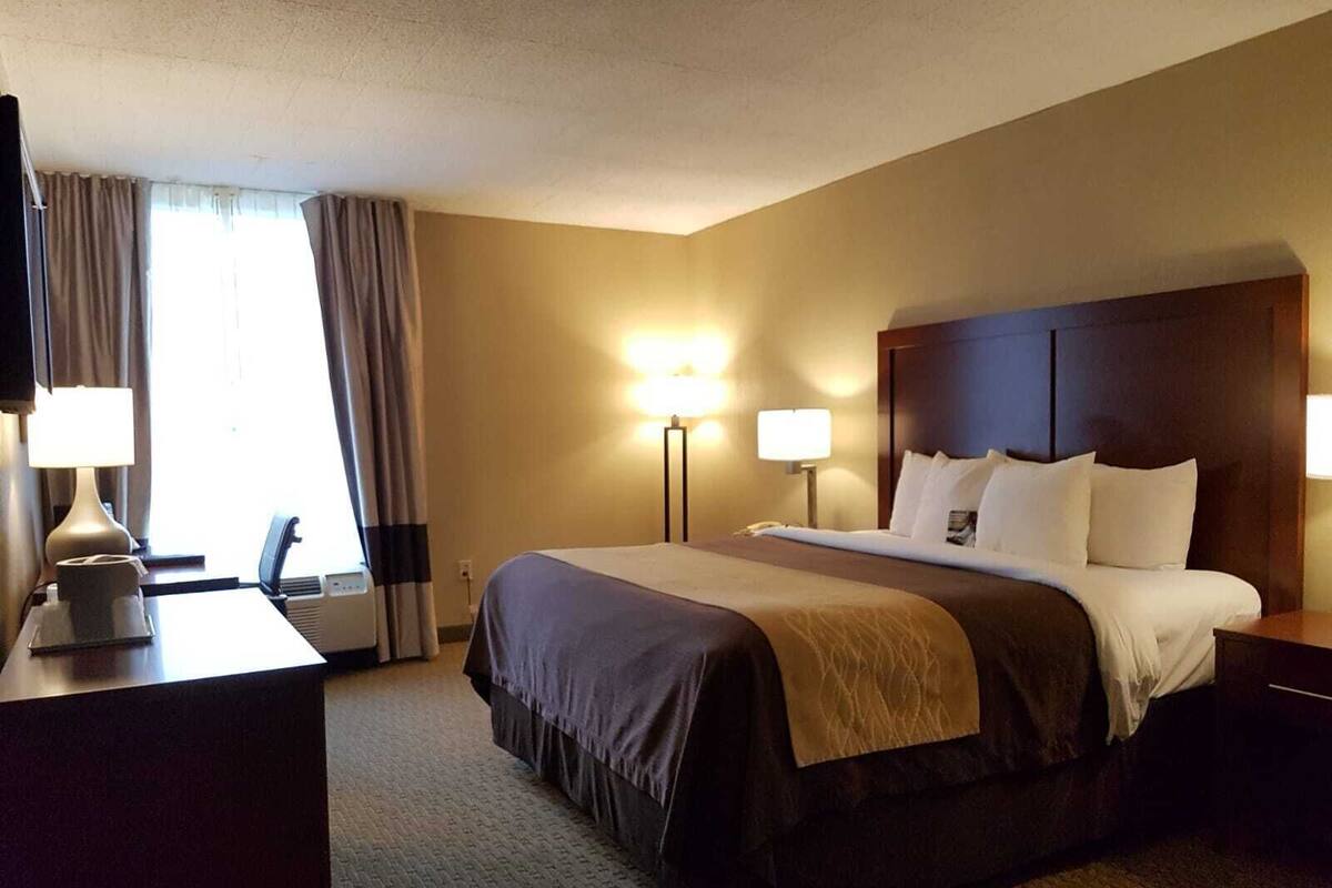 A hotel room with a large bed, two bedside lamps, a desk with a lamp, and a television.