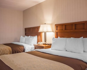 Una habitación de hotel con dos camas, una mesita de noche con una lámpara y un teléfono.