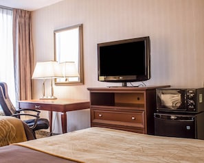 A hotel room with a bed, a desk with a lamp, a television, a microwave, and a chair. - Comfort Inn Wethersfield - Hartford (Wethersfield)