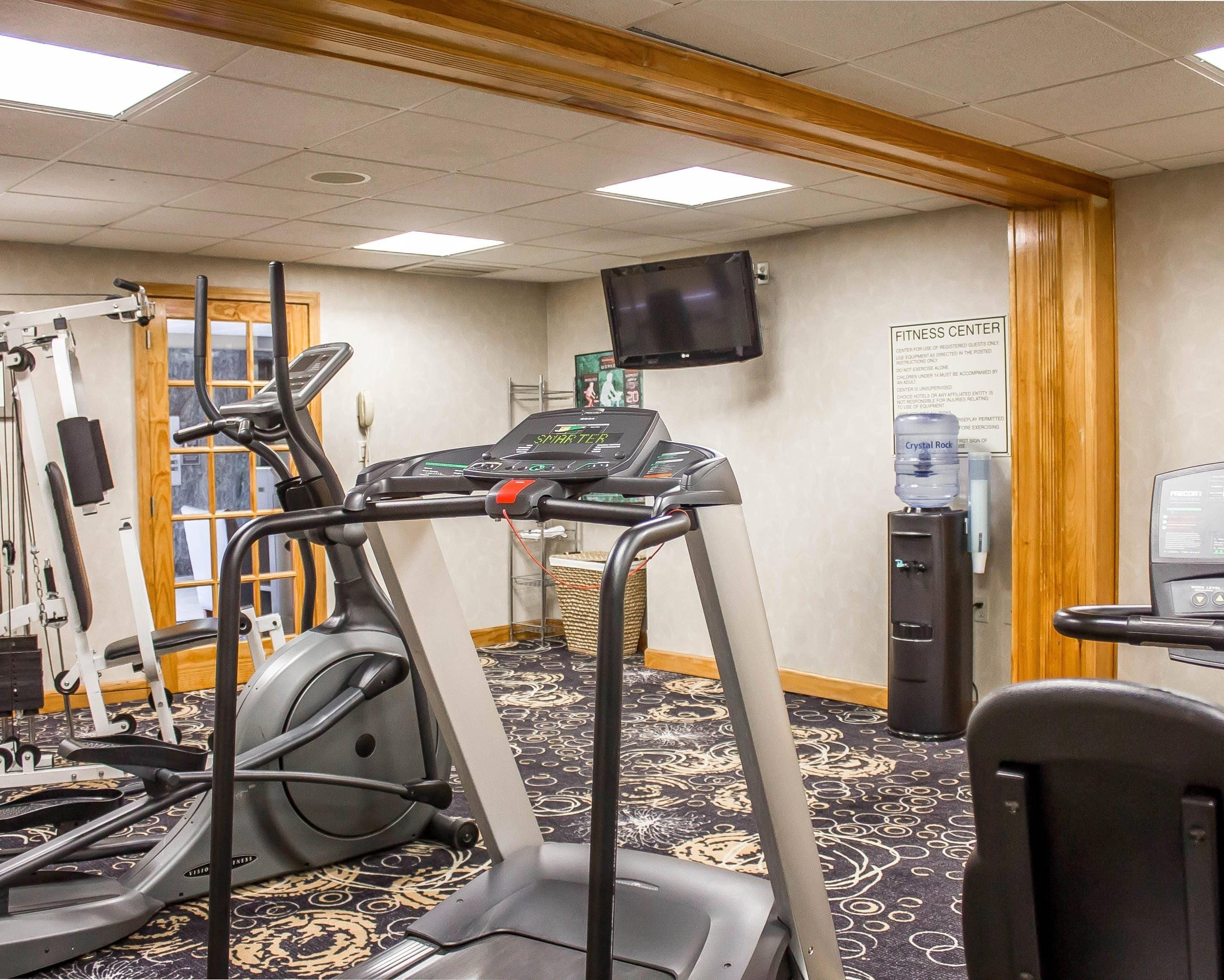 Une salle de sport équipée d’appareils de cardio, d’un téléviseur et d’un distributeur d’eau.