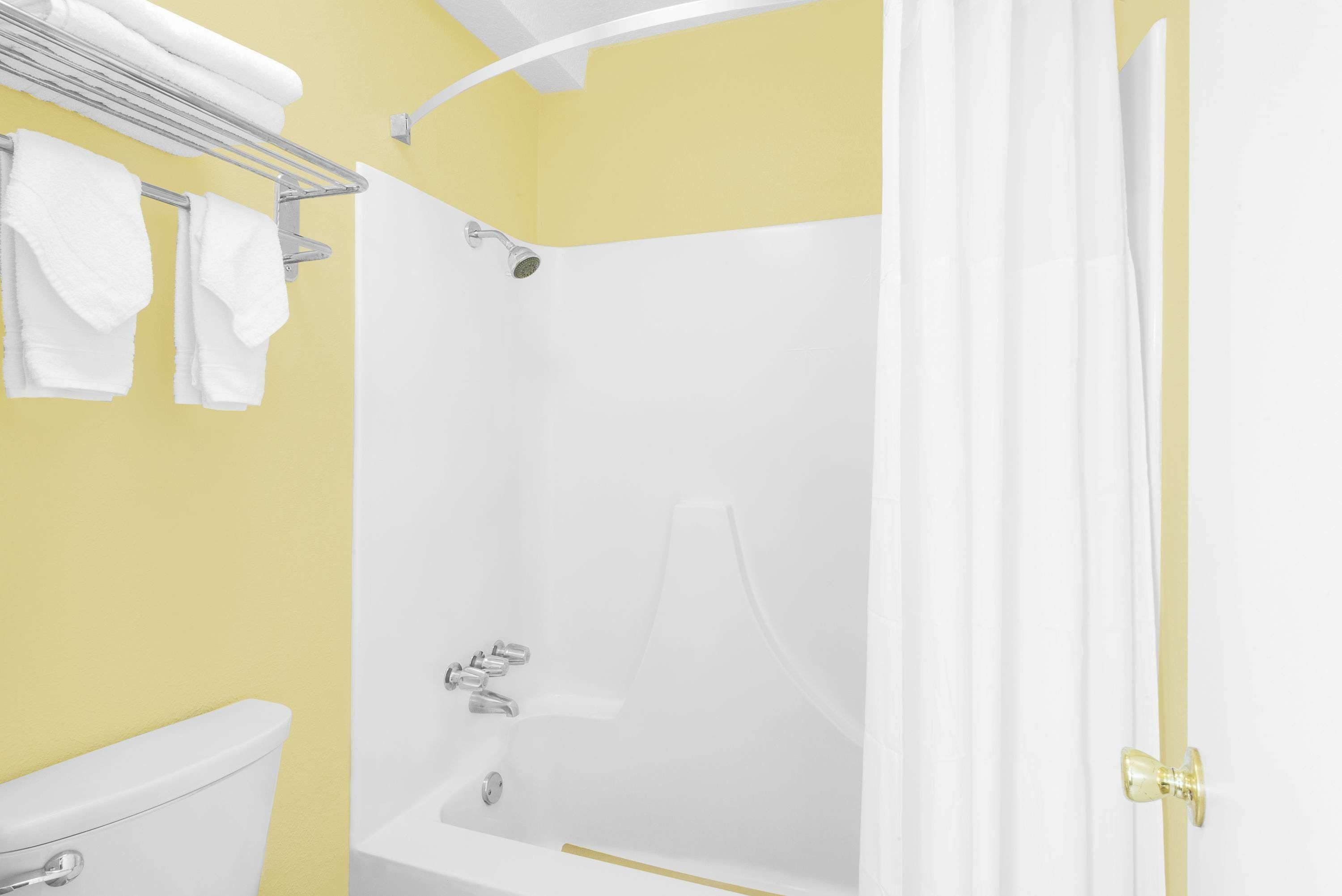 A bathroom with a bathtub, a toilet, and a towel rack with towels.