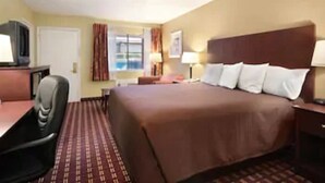 A hotel room with a bed, a desk with a chair, a television, and a window with curtains. - Super 8 by Wyndham Kerrville TX (Kerrville)
