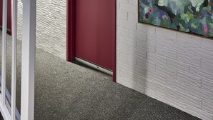 A hallway with a red door, white brick wall, and a large abstract painting. - Central Caleula Motor Lodge (Orange)