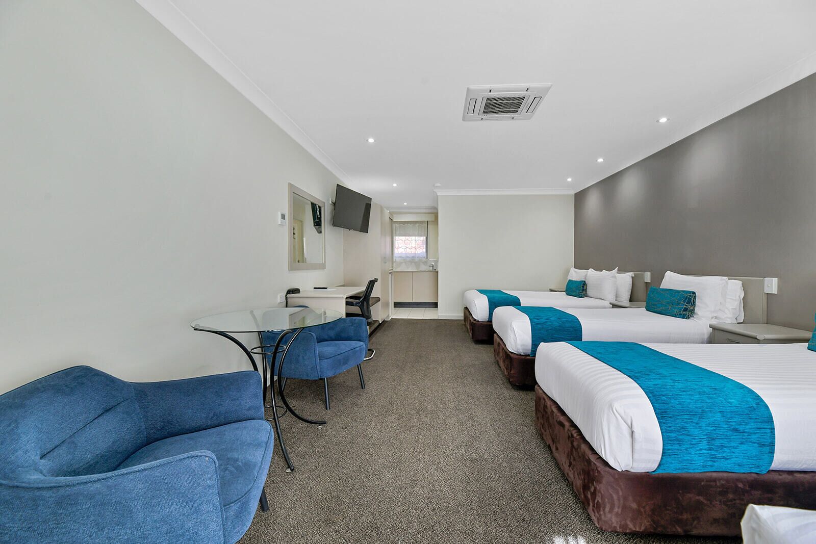 A hotel room with a desk, two beds, a TV, and a bathroom.
