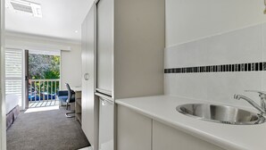 A modern kitchen with a built-in sink and a balcony with a chair. - Central Caleula Motor Lodge (Orange)