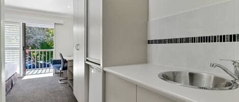 A modern kitchen with a built-in sink and a balcony with a chair.