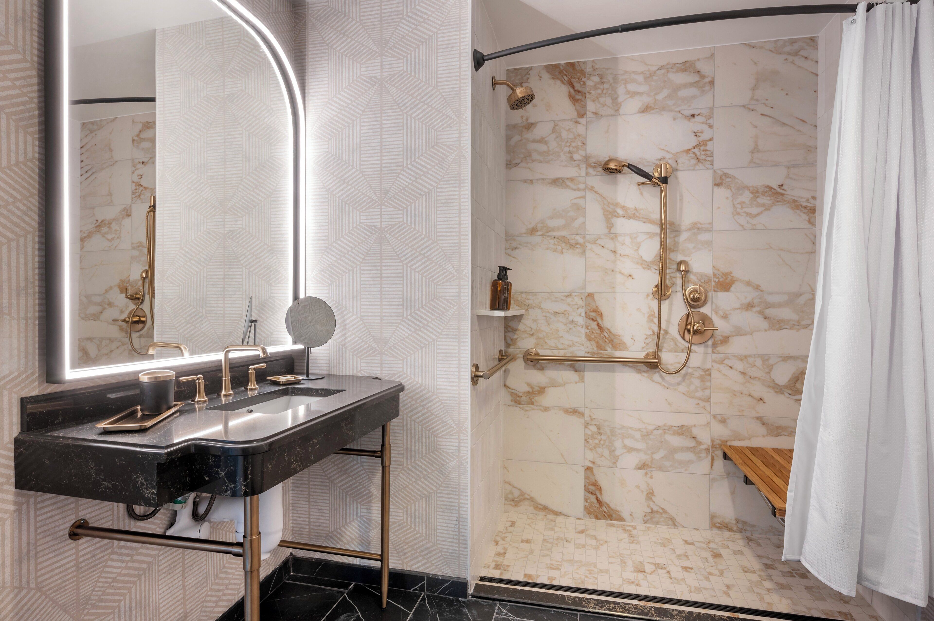A modern bathroom with a curved shower, a vanity with a mirror, and marble walls.
