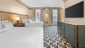 A hotel room with a large bed, a desk, a flat-screen TV, and a patterned floor.