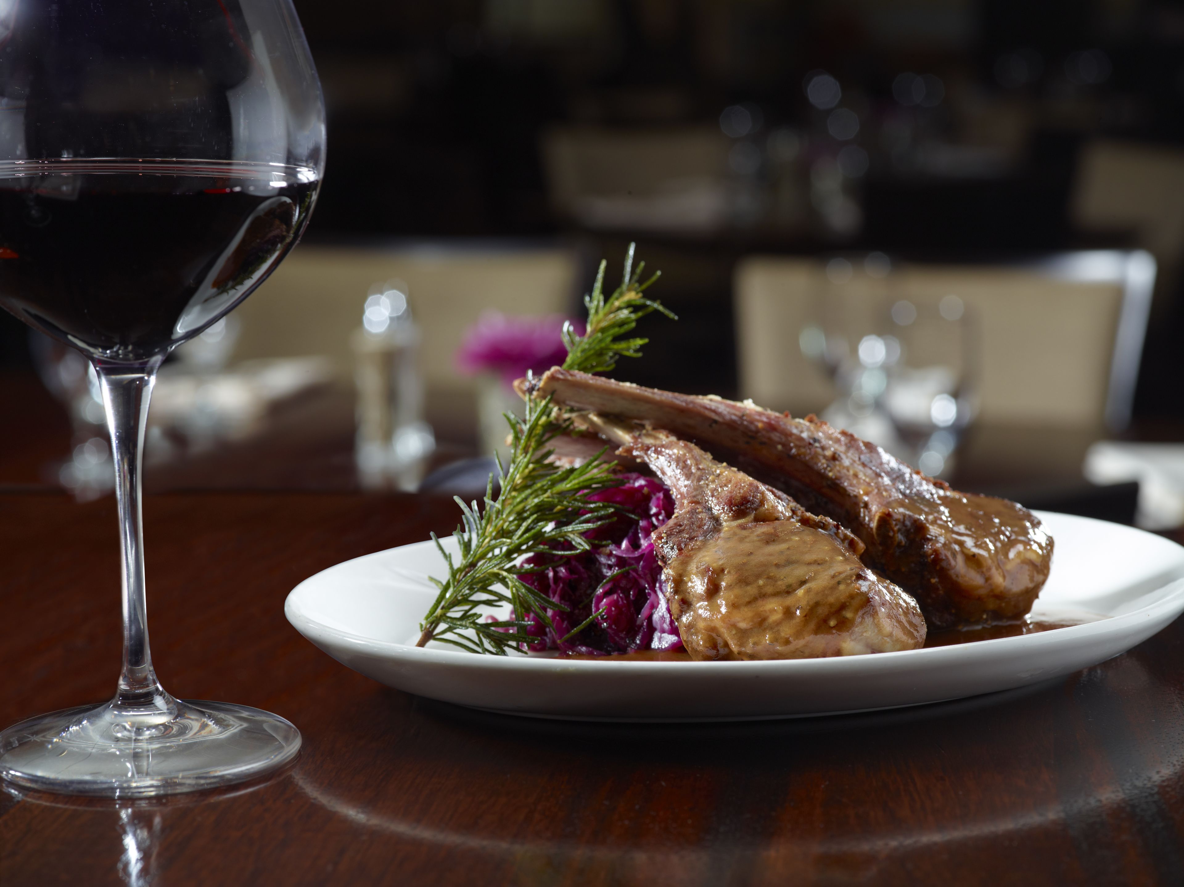 Une assiette de nourriture accompagnée d’un verre de vin rouge, le tout posé sur une table en bois.
