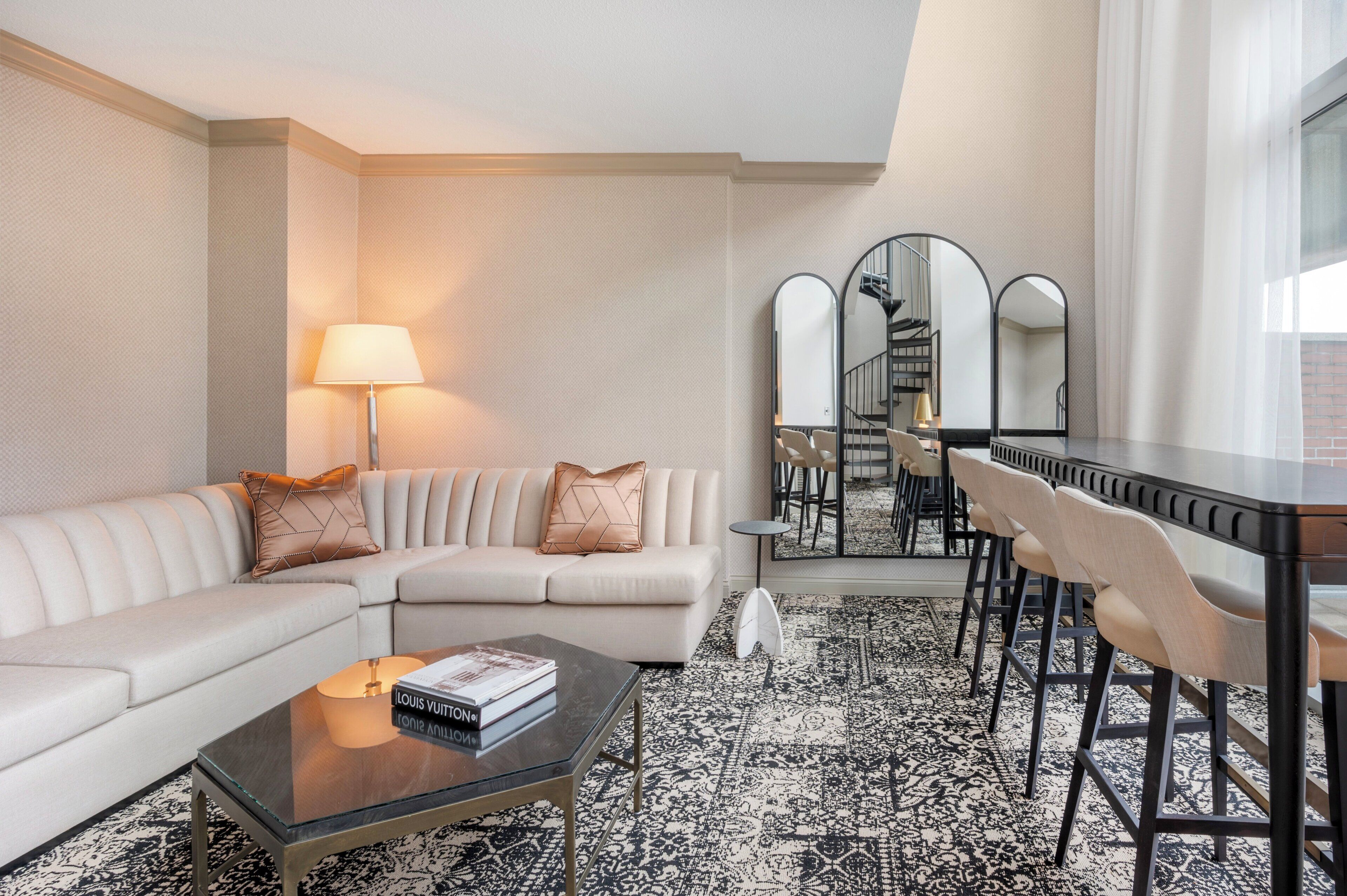 Een moderne woonkamer met een bank, salontafel en een eethoek met stoelen en een tafel.
