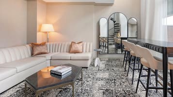 Een moderne woonkamer met een bank, salontafel en een eethoek met stoelen en een tafel.