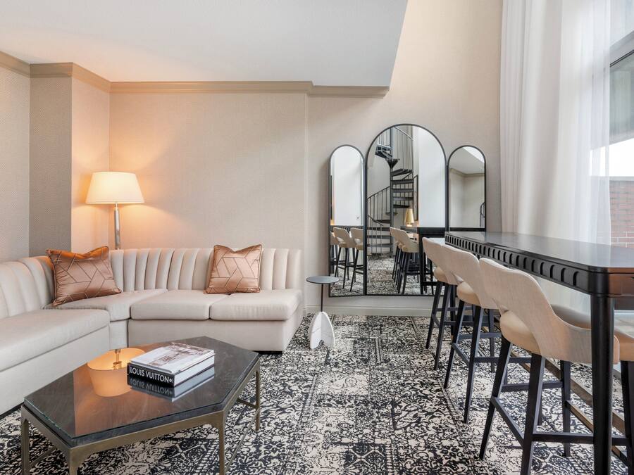 Een moderne woonkamer met een bank, salontafel en een eethoek met stoelen en een tafel.