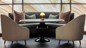 Una sala de estar moderna con una mesa redonda, dos sillones y un sofá.