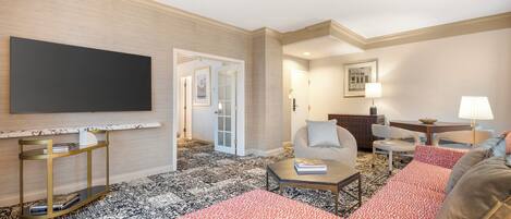 A modern living room with a flat-screen TV, a sofa, a coffee table, and a patterned rug.