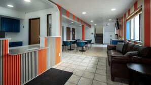 Un interior moderno con mostrador de recepción, zona de estar y una escalera que conduce a un nivel superior.