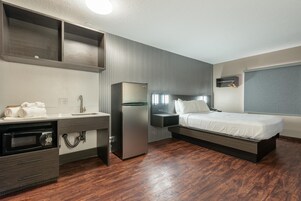 Una habitación de hotel moderna con kitchenette, una cama y un ventanal grande.