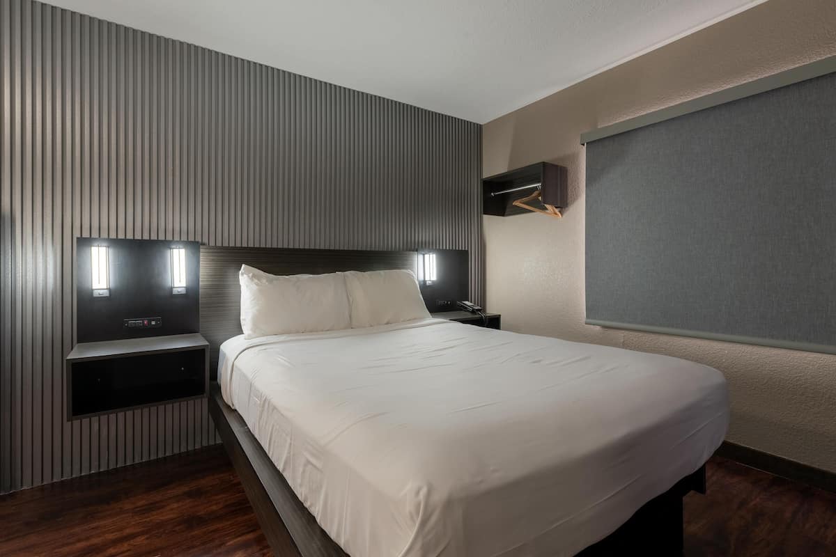Een moderne hotelkamer met een groot bed, een ingebouwde televisie en een garderobe met spiegel.
