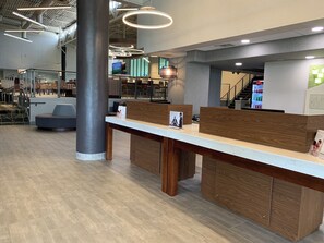A reception area with a marble counter, wooden paneling, and a staircase in the background.