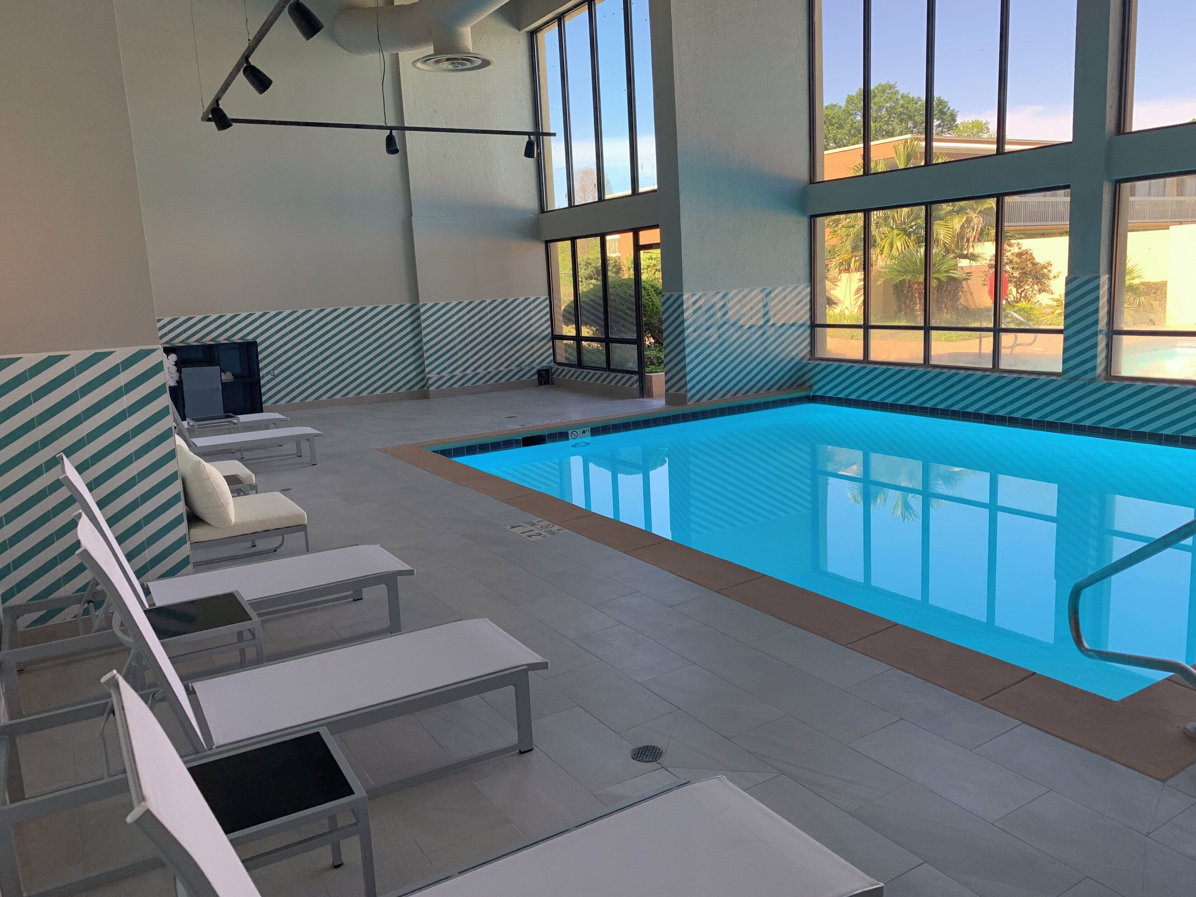 Un espace piscine avec des chaises longues et une vue sur l’extérieur.