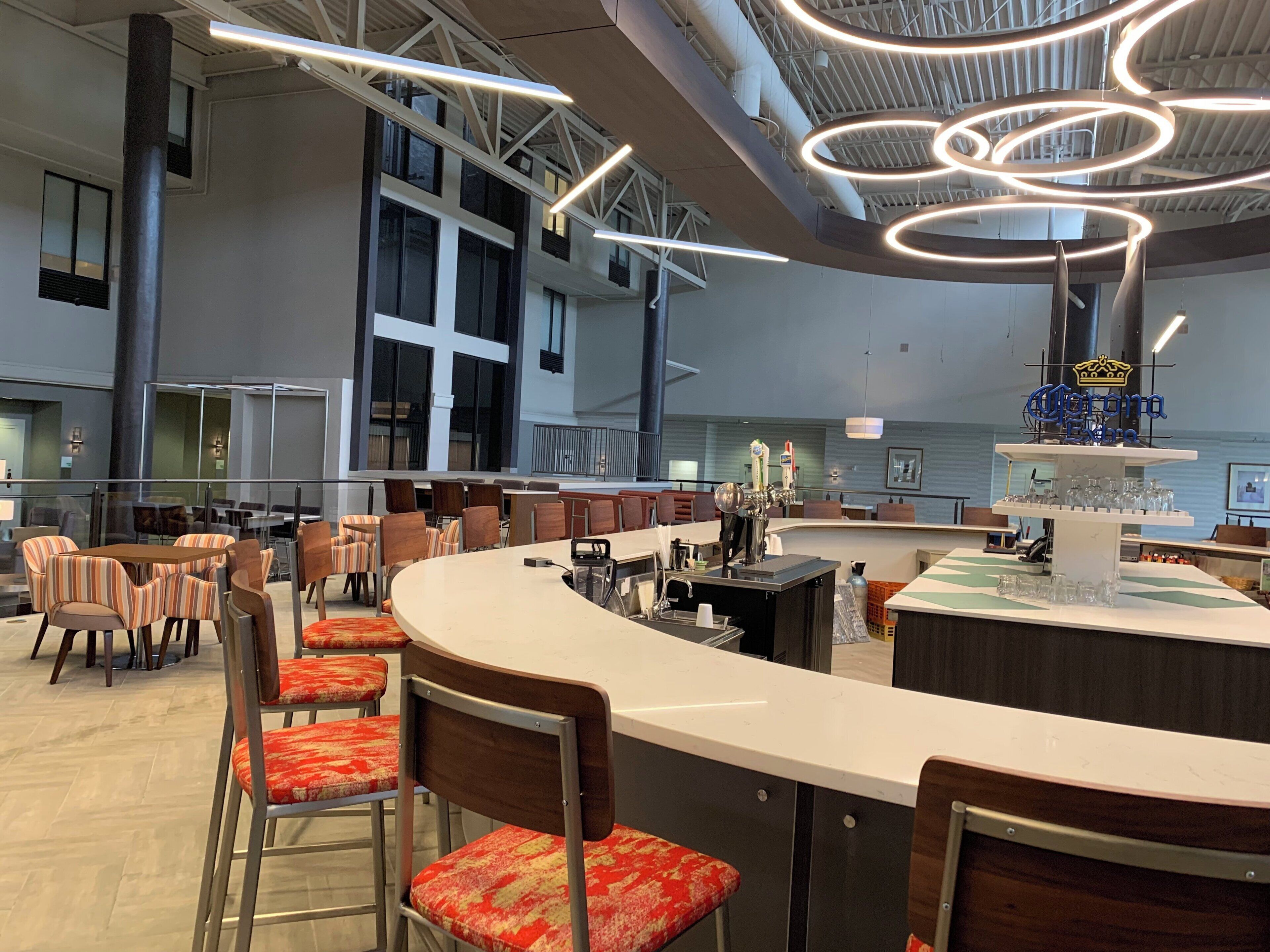 A modern bar area with a curved counter, multiple seating options, and a ceiling with circular light fixtures.