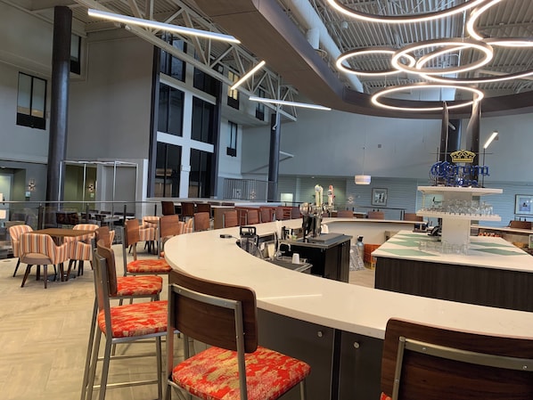 A modern bar area with a curved counter, multiple seating options, and a ceiling with circular light fixtures.