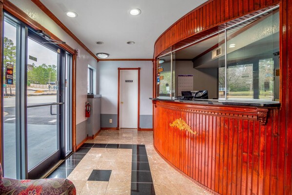 A reception area with a wooden reception desk, a glass door entrance, and a tiled floor.