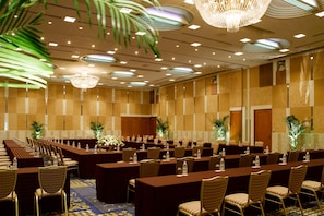 A conference room with long tables and chairs, equipped with water bottles and floral centerpieces.