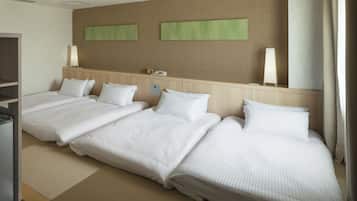 A hotel room with three beds, a wooden headboard, a flat-screen TV, and a wall-mounted phone.