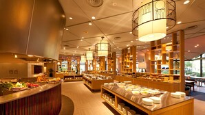 Un restaurant moderne doté d'un buffet central, d'étagères en bois et de luminaires suspendus.