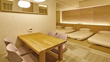 A hotel room with a wooden table, chairs, a large mirror, and a bed with pillows.