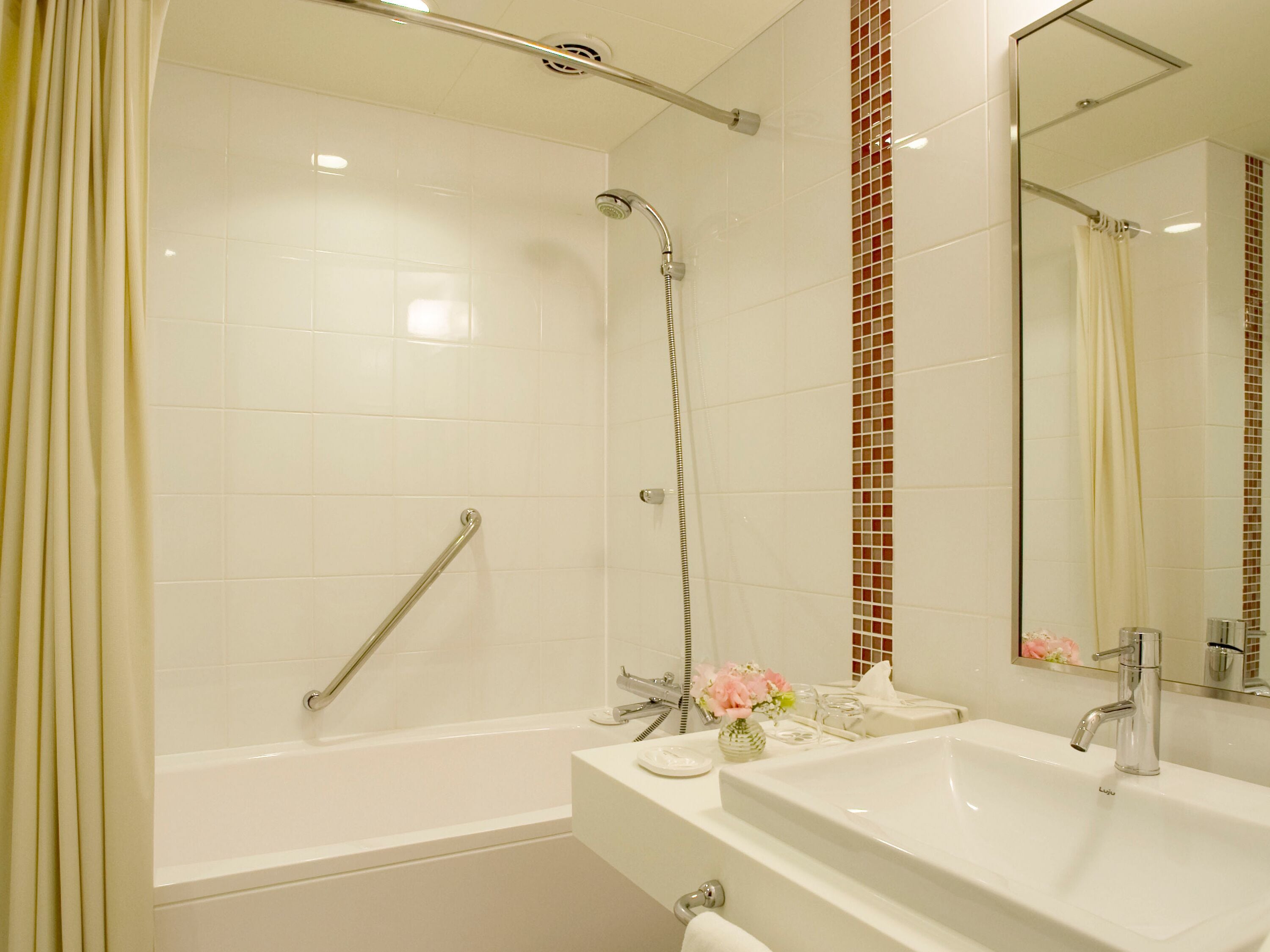 A modern bathroom with a bathtub, shower, and two sinks.