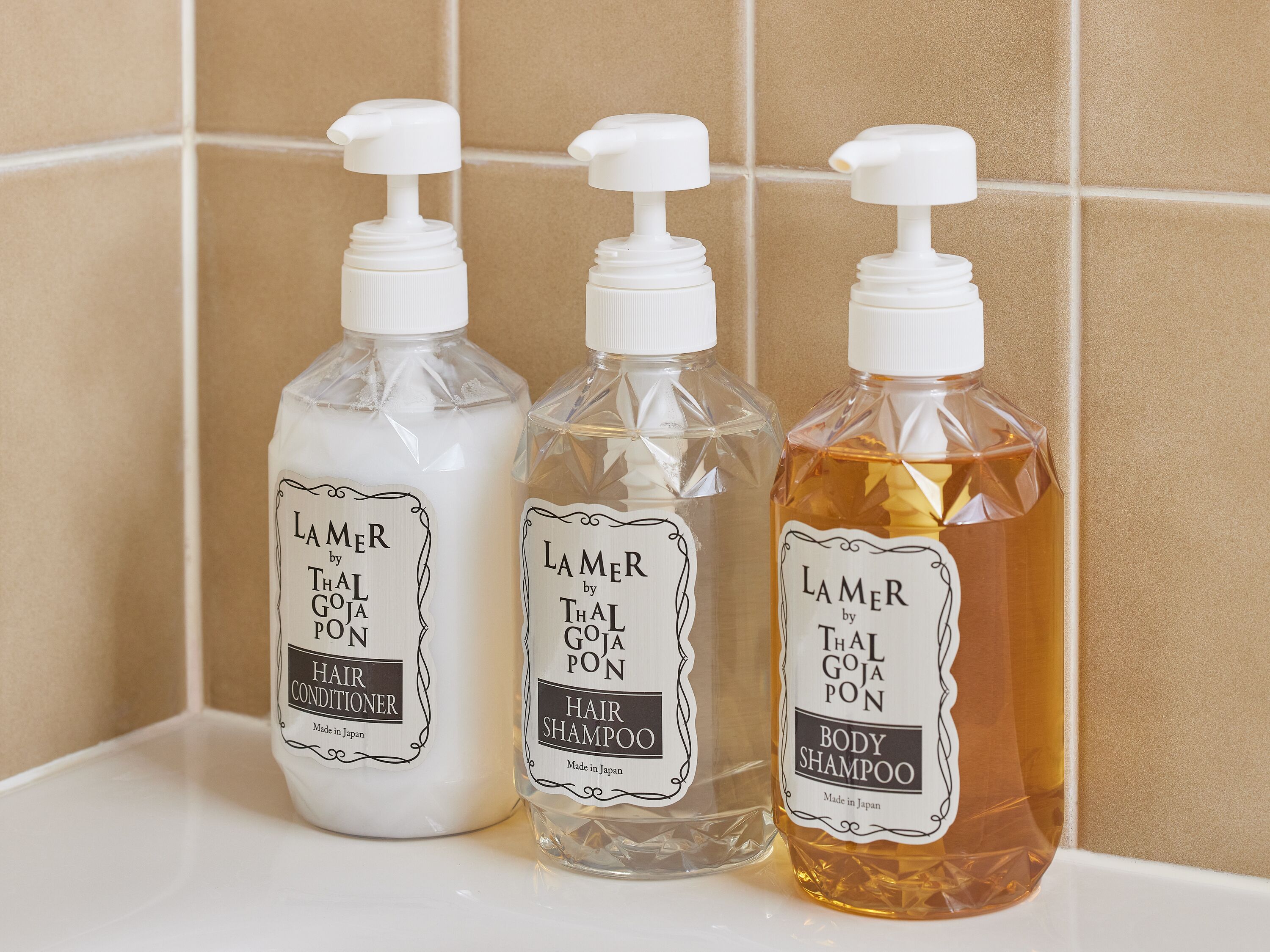 Three bottles of Lamer by Thal Goja Pon hair products on a white shelf.