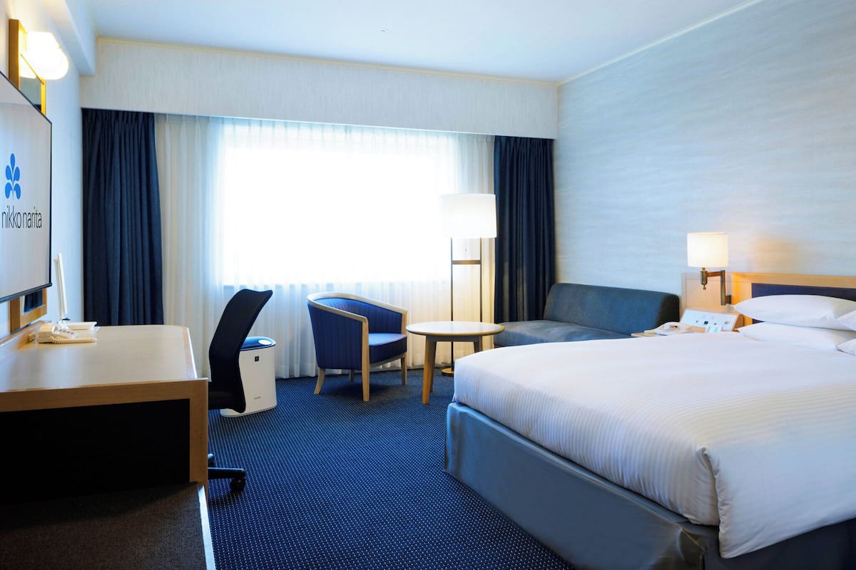 Ein Hotelzimmer mit Bett, Schreibtisch, Stuhl und einem kleinen Tisch.