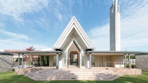 Una chiesa moderna con un campanile imponente e un ingresso a forma triangolare.