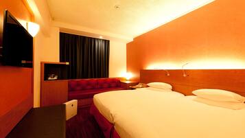 Ein Hotelzimmer mit einem Bett, einem Fernseher, einem Schreibtisch und einem roten Sofa.