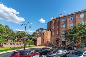 A brick building with a sign reading "HOULIHAN'S" and a parking lot with several cars.