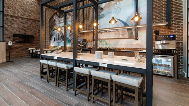 A restaurant with a brick wall, wooden bar stools, and pendant lighting. - Columbus Marriott (Columbus)