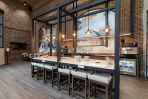A restaurant with a brick wall, wooden bar stools, and pendant lighting. - Columbus Marriott (Columbus)