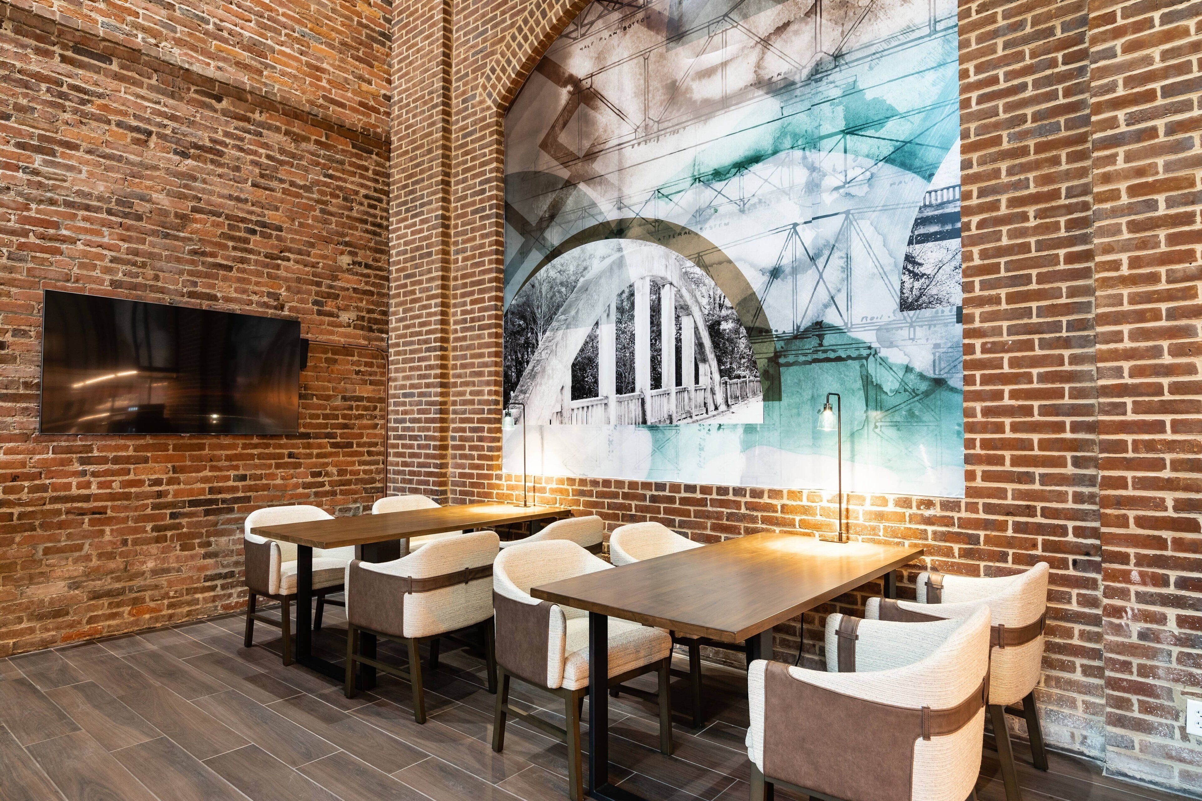A restaurant with brick walls, a mural of a bridge, and multiple tables and chairs.