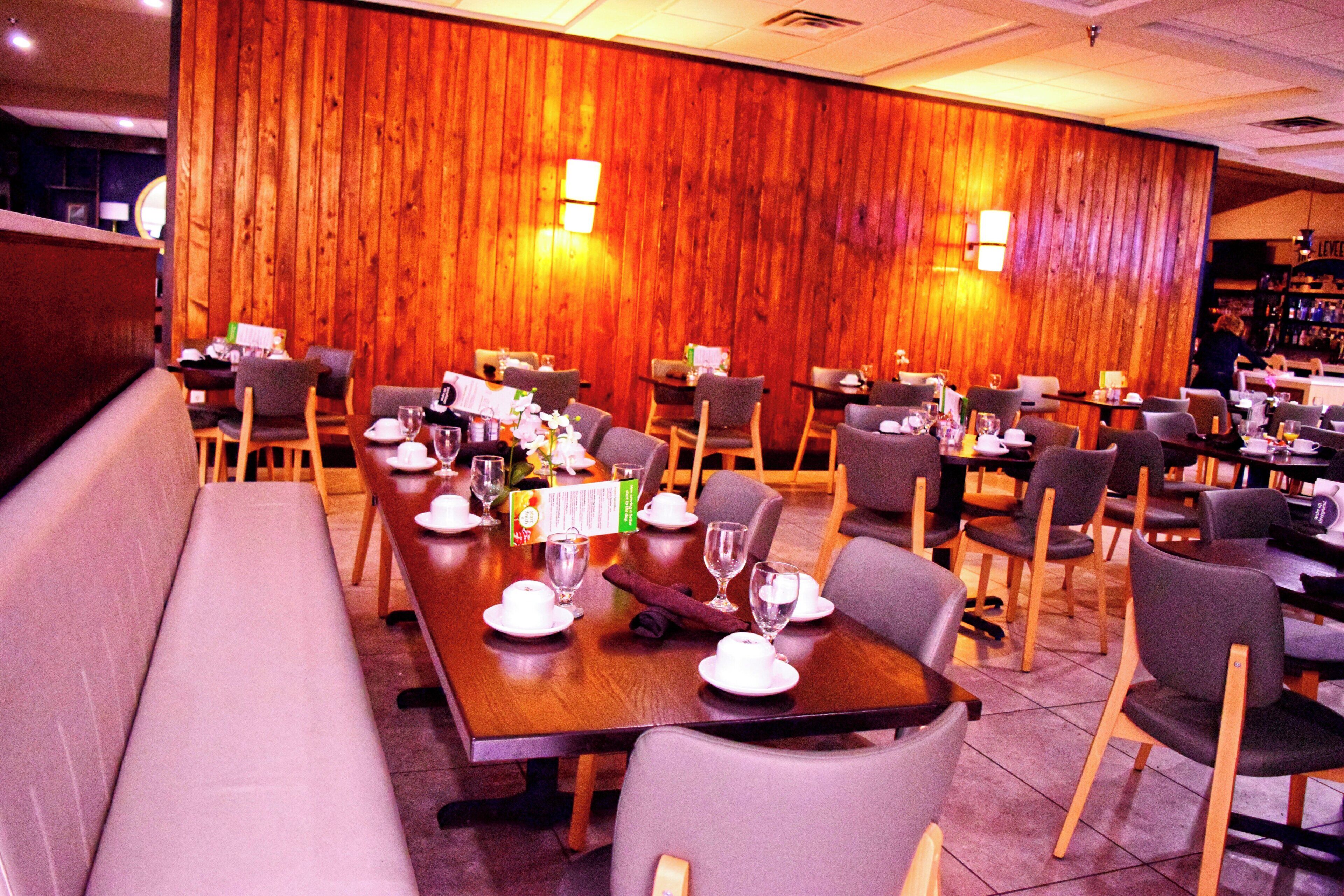 A restaurant with wooden panel walls, multiple dining tables, and chairs.